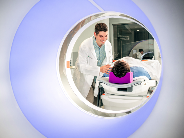 A physician leaning over to guide a patient through a CT machine