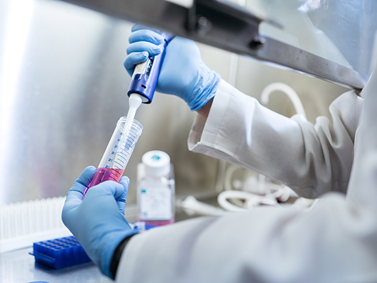 Back, School of Health Professions' Biomedical Sciences (BMD) program student is pipetting under a hood in a laboratory in the Zeigler Research Building, 2018.