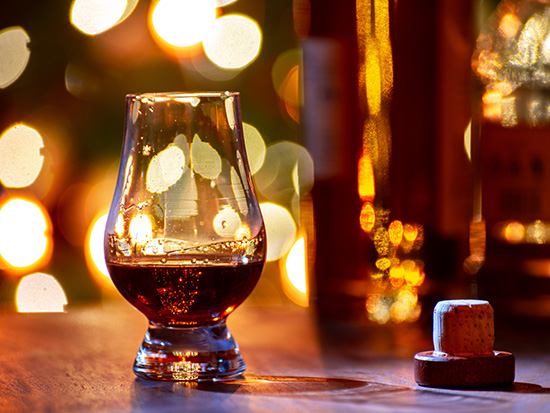 Glasses of scotch whisky served in bar with lights in background.