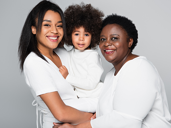 african american girl in hands of happy mom and granny looking at camera isolated on grey