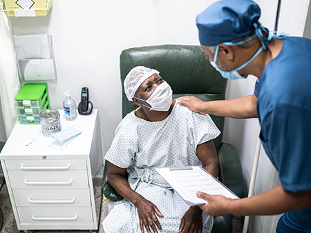 Patient sitting in chair speaking to physician. 