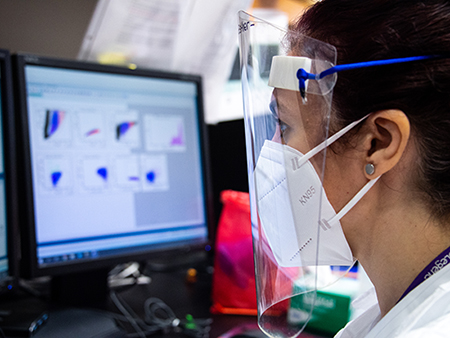 From side, Dr. Esther Zumaquero Martinez, PhD (Instructor, Microbiology) is wearing a PPE (Personal Protective Equipment) face mask and shield while conducting research related to COVID-19 (Coronavirus Disease) in the Lund Laboratory in Shelby Biomedical Research Building, May 2020.