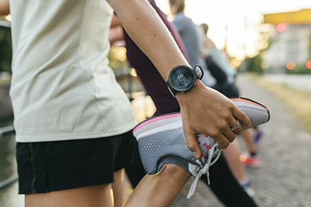 A close up of a woman stretching her legs before going on a run through the city.