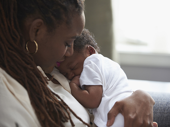 Black mother holding sleeping baby son