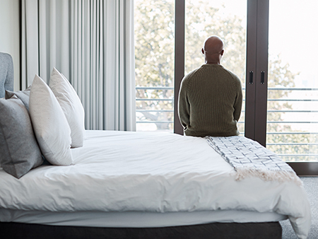 Rearview shot of a mature man looking through a window in a bedroom at home