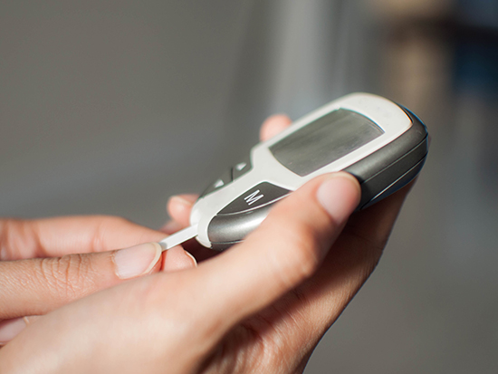 A close-up of a young woman is using a blood sugar device