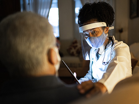 Female doctor visiting her patient at his home - appointment with digital tablet