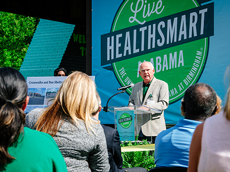 UAB President Ray L. Watts speaks from behind a podium. 