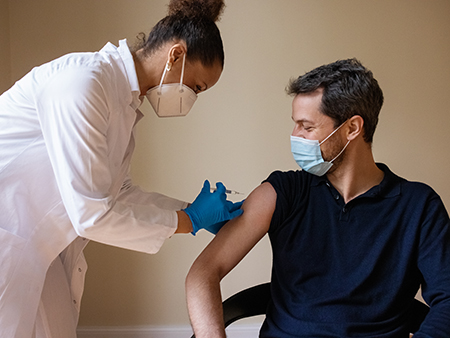 Doctor giving an injection to the patient at hospital. Healthcare worker giving covid-19 vaccine to a man in medical clinic.