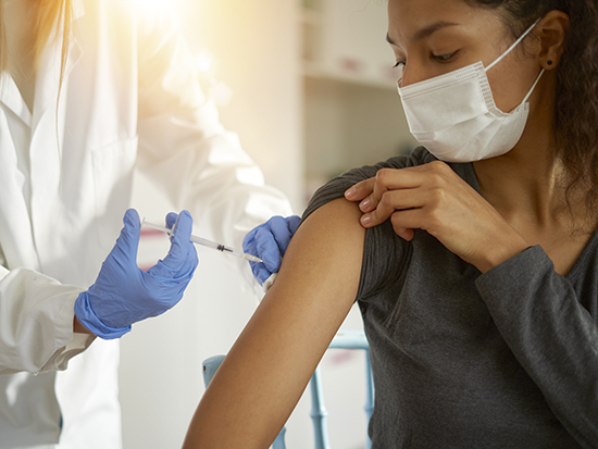 Young woman wearing mask getting vaccinated.