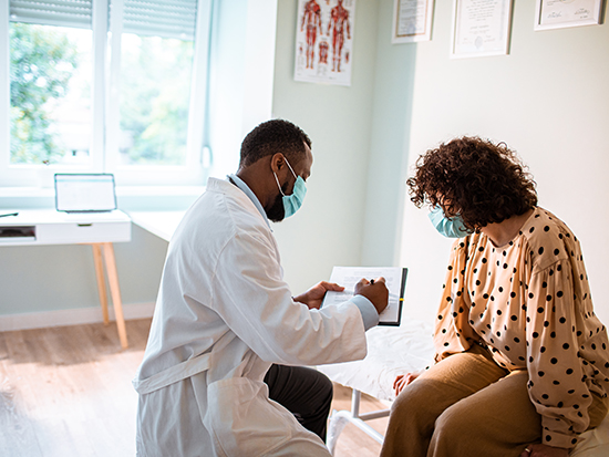 Close up of a doctor doing a medical exam while both him and the patient are wearing protective masks