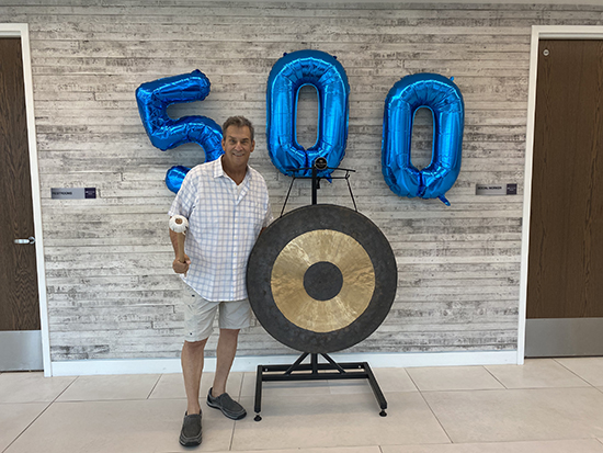 Patient standing in front of balloons that spell out 500. 