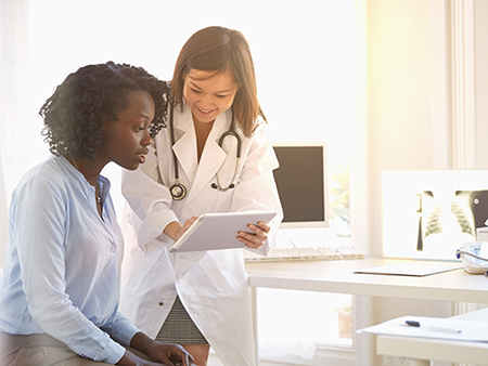 Doctor and woman reading digital tablet