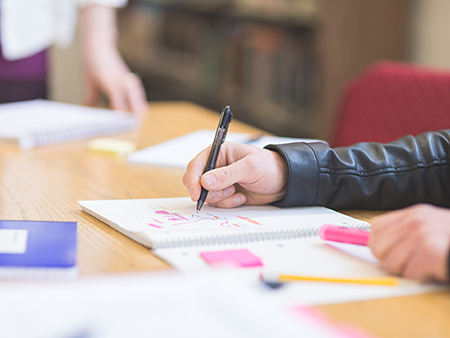 A student carefully writes up notes in preparation for his next class