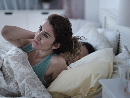 Woman rubbing her neck in bed