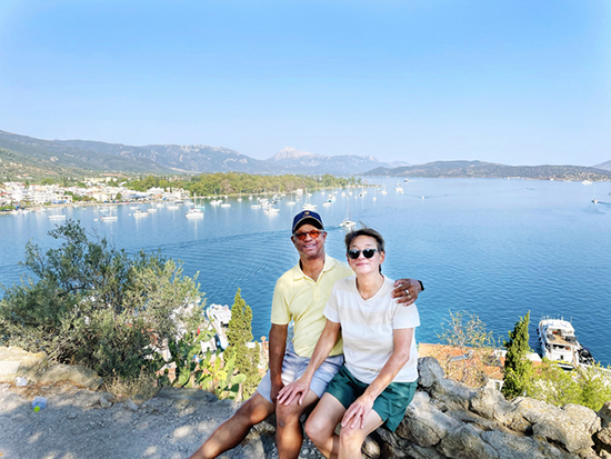 Male and female sitting on rock ledge overlooking ocean.