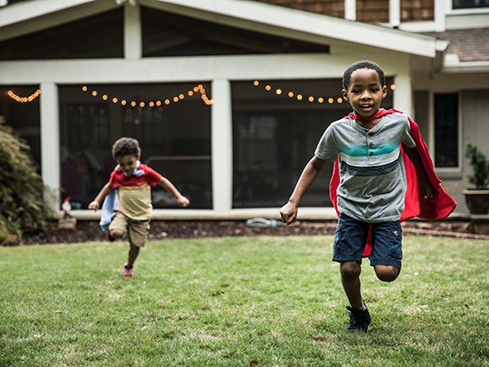 Young boys (3 yrs and 6yrs) in capes playing in backyard