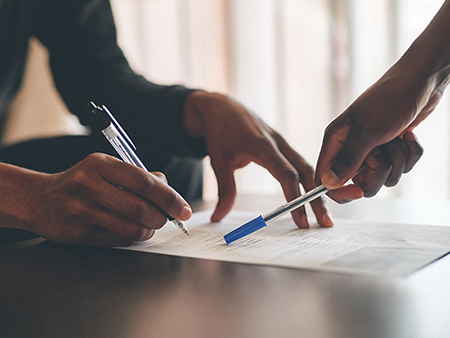 Cropped shot of an unrecognizable man filling a document with the help of a financial advisor at home