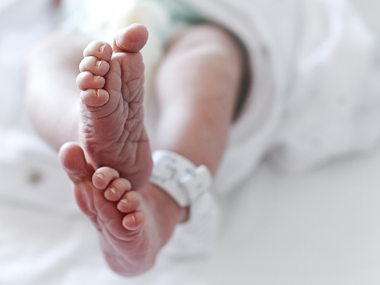 Newborn baby boy at hospital with identity tag on feet, close up