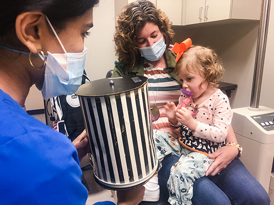 Baby sitting in mom's lap with doctor examining her. 