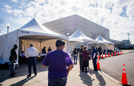 Back, a line of people are standing beside white tents at the UAB COVID-19 Vaccination Site at Parker High School on February 10, 2021/.