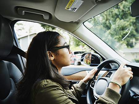 Young woman sitting in drivers seat of car waiting fro driving lesson