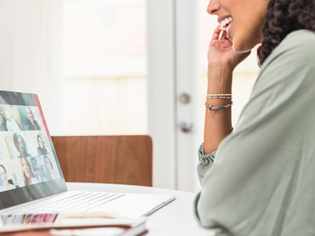 An unrecognizable young adult woman enjoys a video conference with colleagues during the coronavirus epidemic.