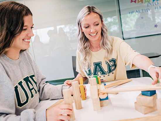 Two smiling female students are participating in a team-building experiment.