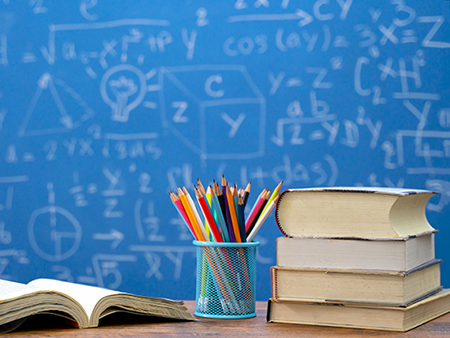 Back to school supplies. Books and blackboard on wooden background