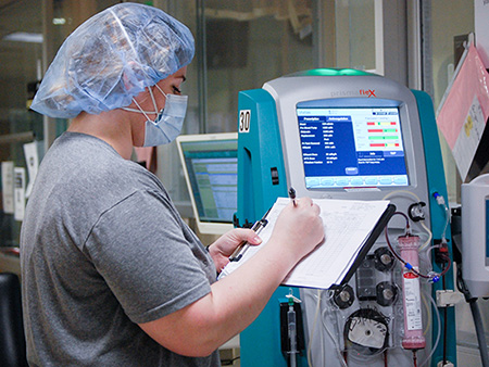 From side, female nurse is wearing Personal Protective Equipment (PPE) while working in the Hospital during the COVID-19 (Novel Coronavirus) pandemic, March 2020.