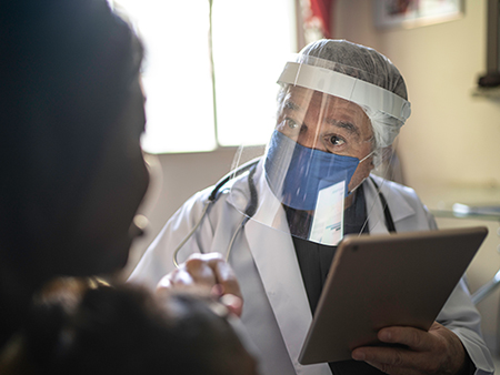 Doctor wearing protective face mask on medical consultation at home