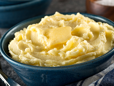 A bowl of delicious mashed potatoes with melted butter.