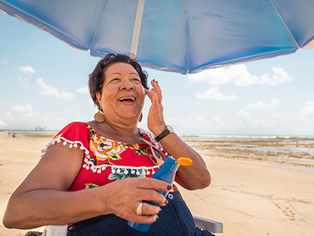 Older adult woman putting sunscreen on her face. 