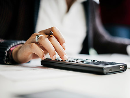 A close up of a student using a calculator and studying in a public library.