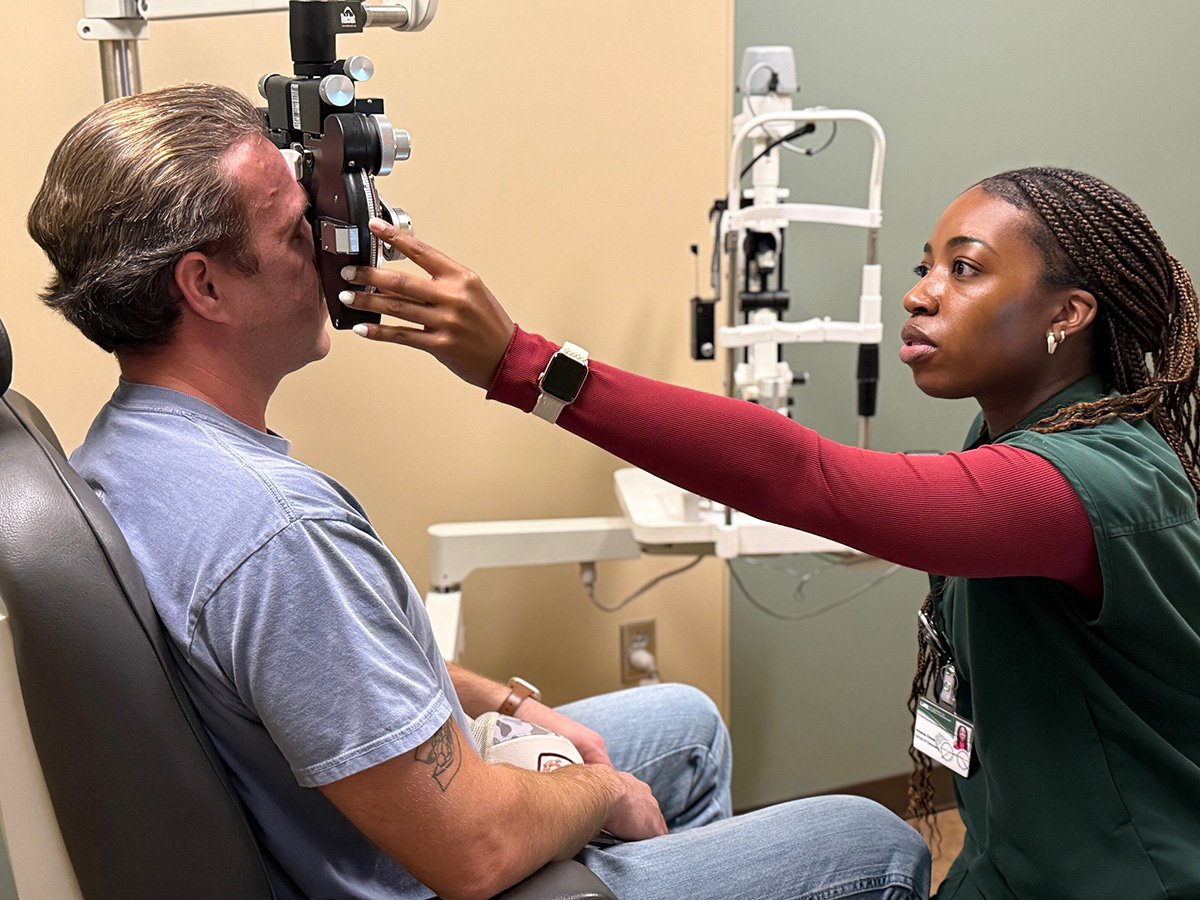 Black women examining a white man's eye at the clinic