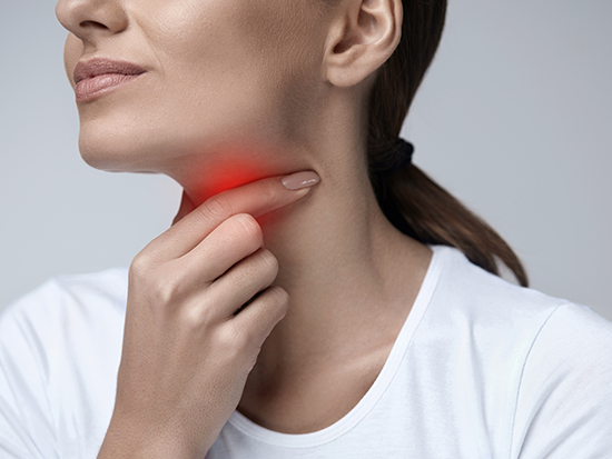 Woman grabbing throat with red illumination around throat area