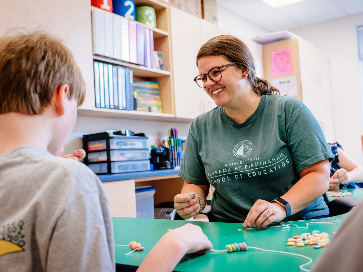 Female Education student is instructing several special education children in an art project at a summer camp