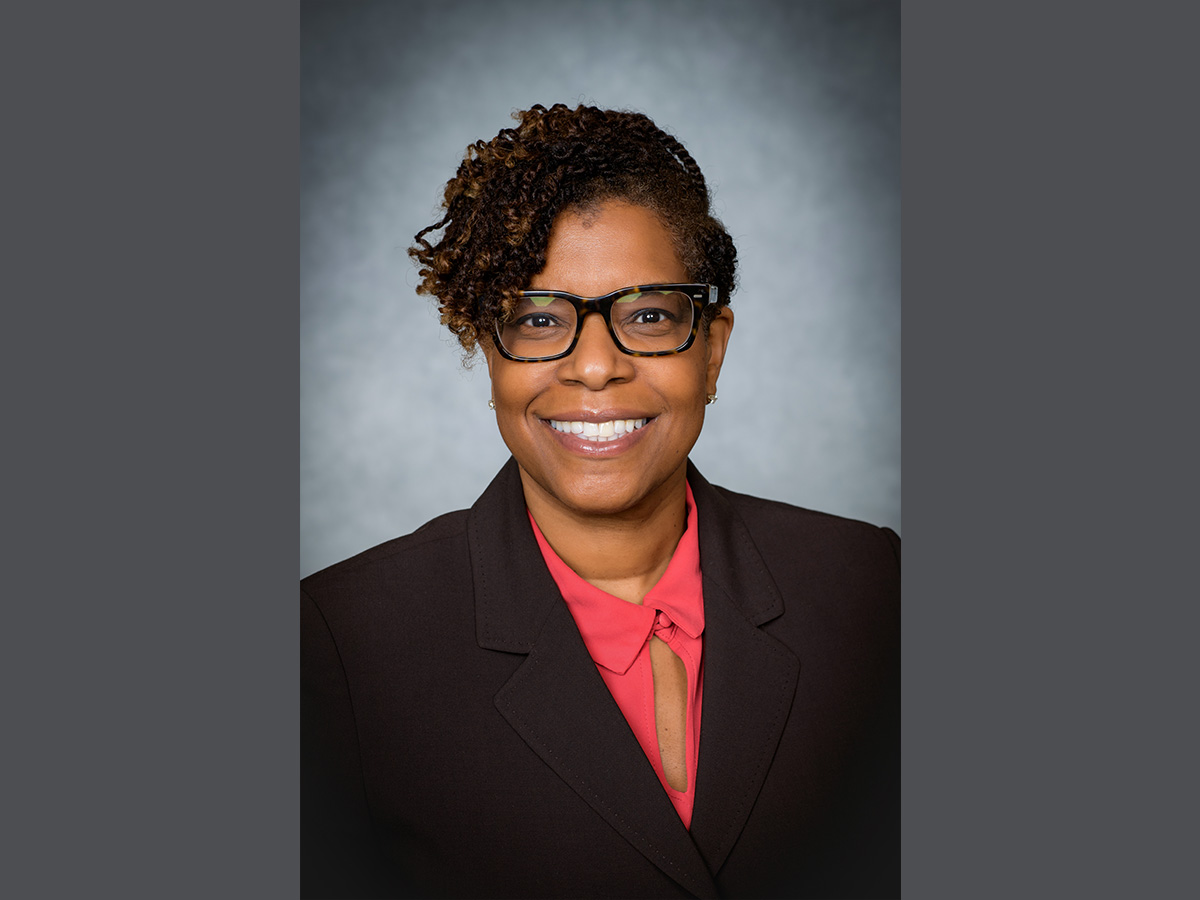 Headshot of Tracey Wilson, M.D., in a peach colored top, black blazer, and gray background.