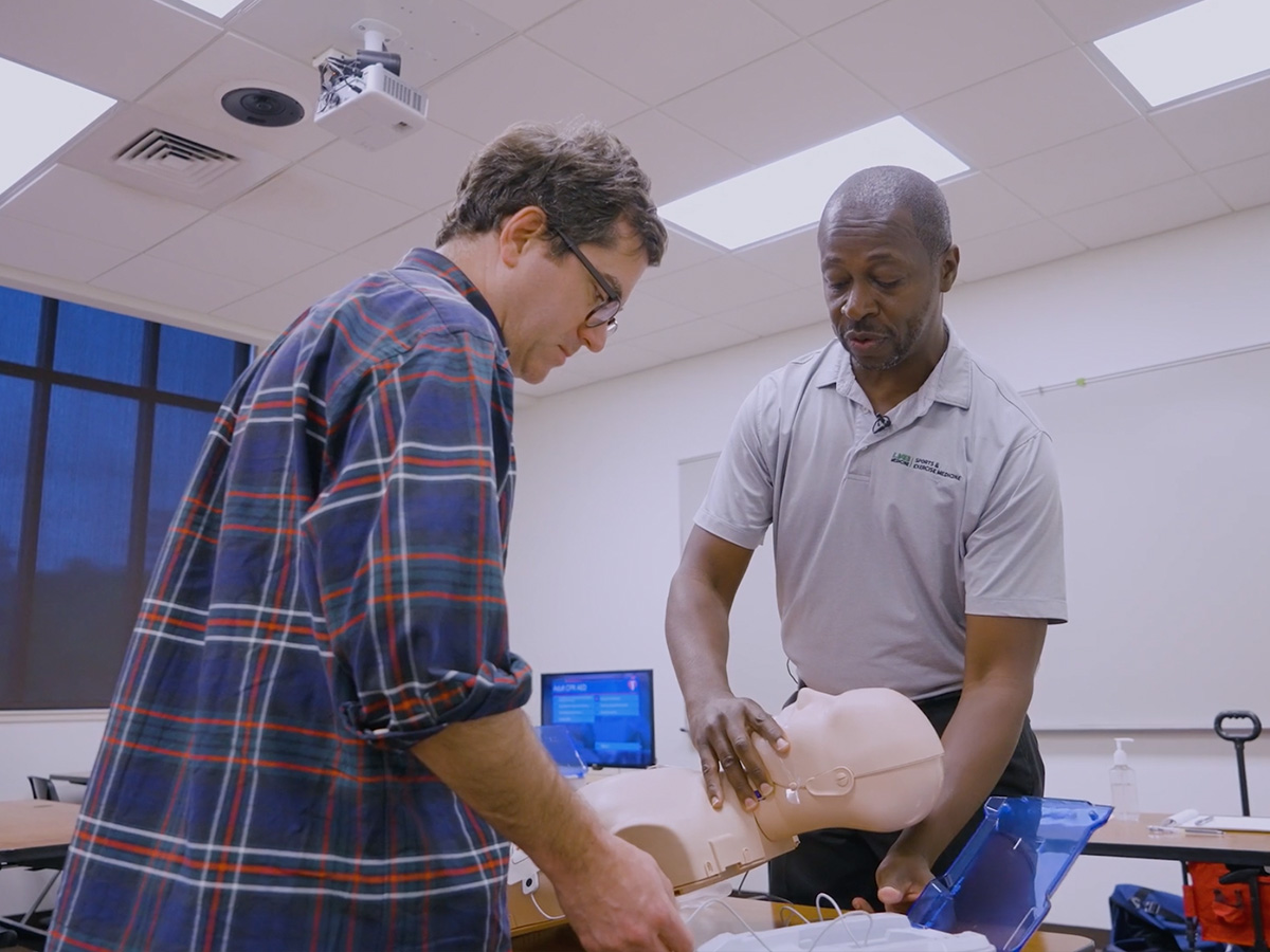 Man using mannequin to teach CPR
