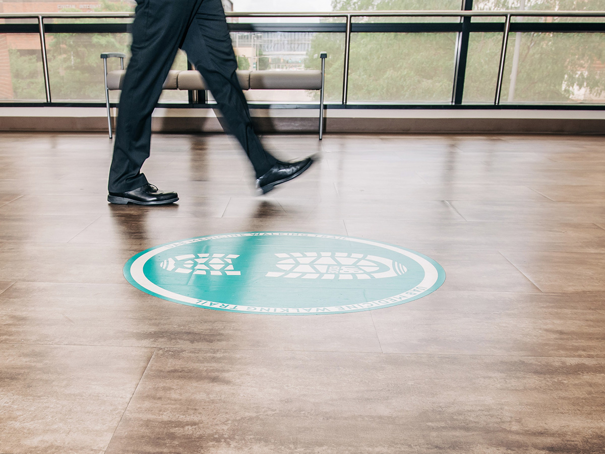 Close-up, action shot of legs and feet of person walking on floor signage decal that reads 