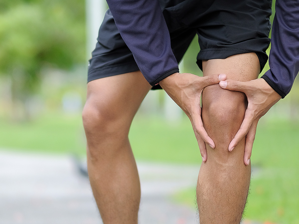 Man grabbing knee in park.