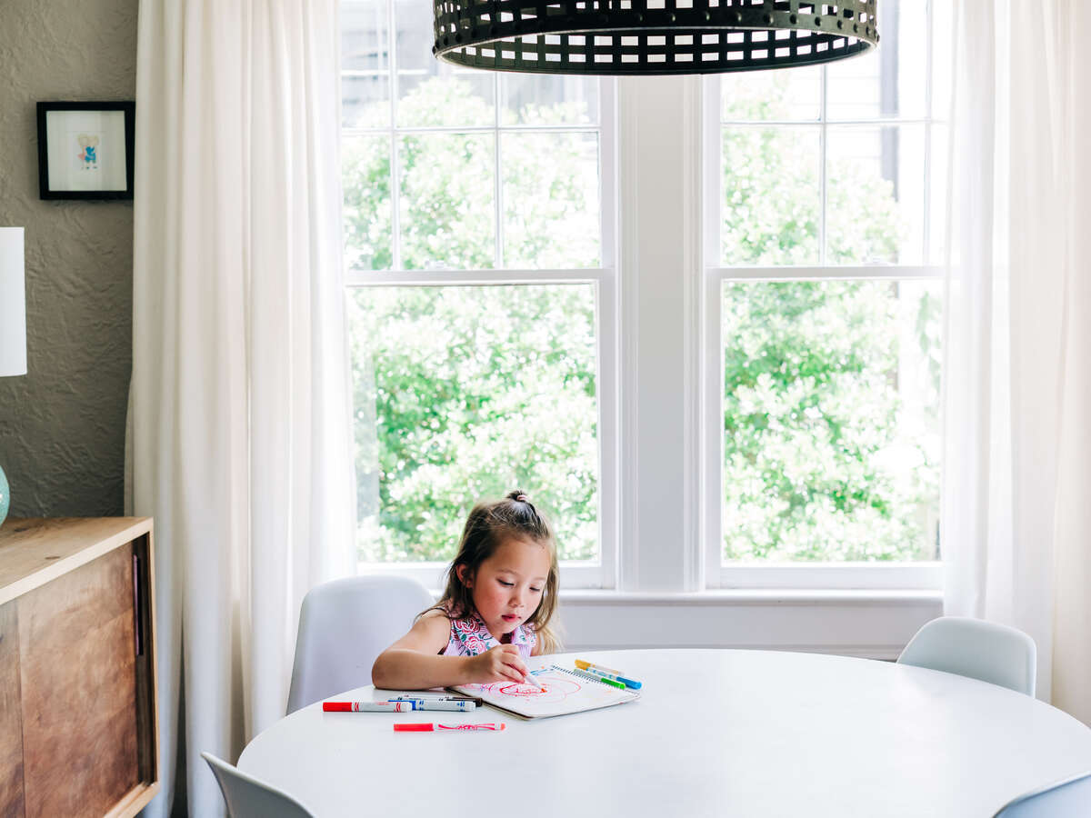 Child drawing with markers sitting at a round table. 