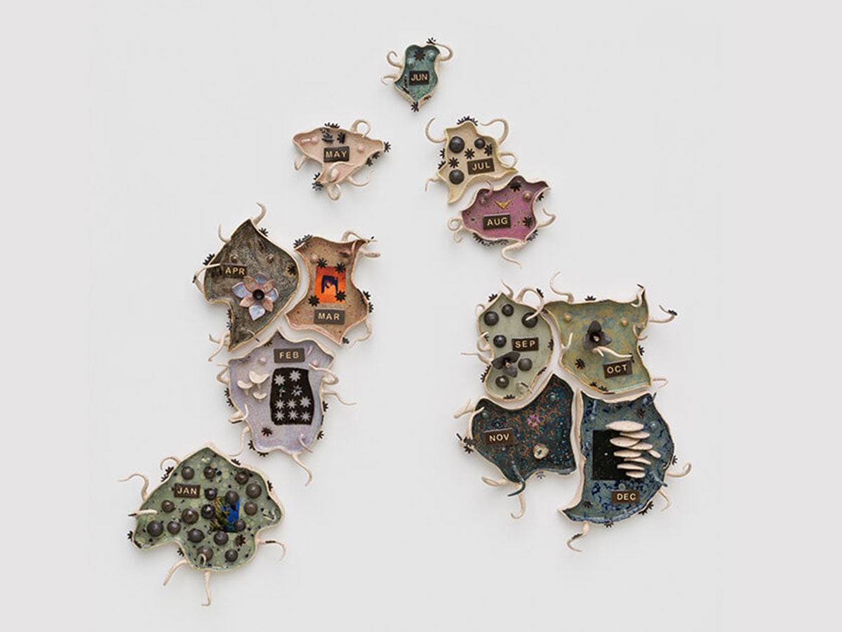 Works by the artist, playful small sculptures with various designs and each with a month of the year, are displayed.