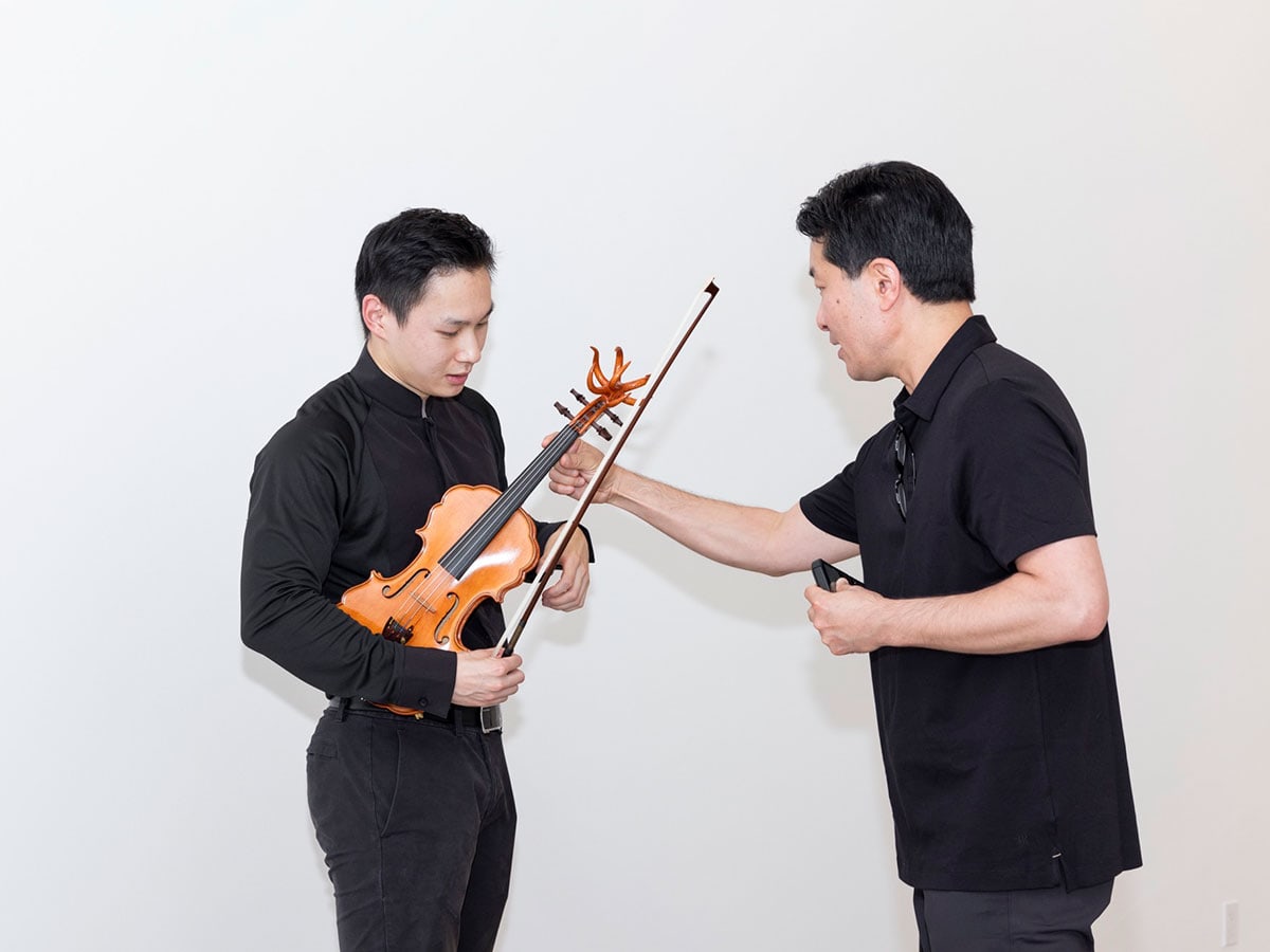A musician holds the butterfly violin crafted by artist Minkyu Lee as the artist touches the instrument.