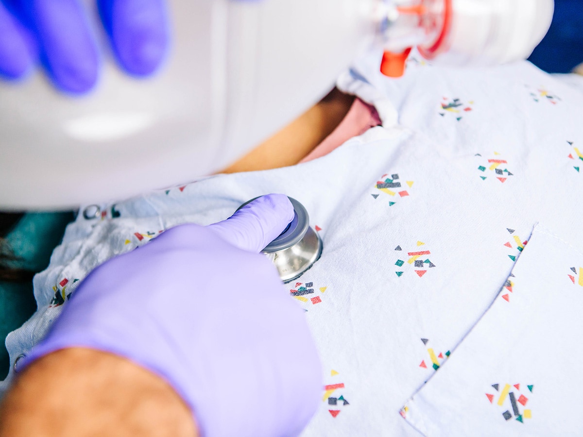 Hands of a doctor using a stethoscope and an Ambu bag on a patient.