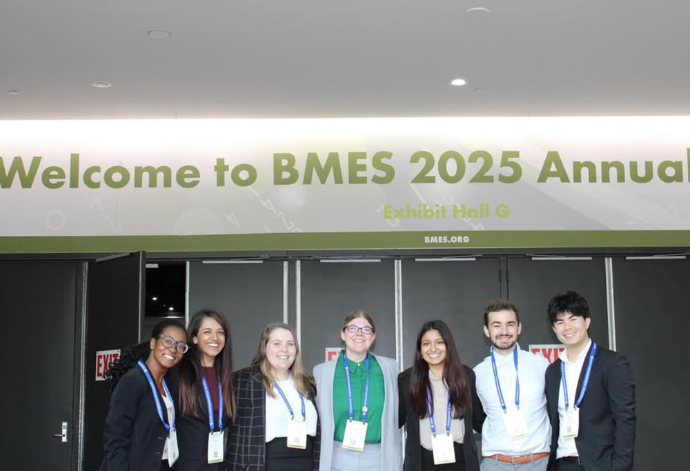 Sewell-Loftin lab members pose in front of a sign reading Welcome to BMES 2025 Annual Conference