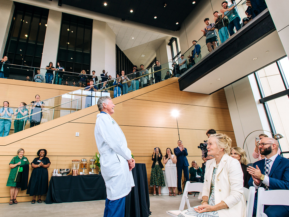 A crowd in the Volker Hall Atrium cheers as Dr. Marnix Heersink looks around and Mary Heersink looks on