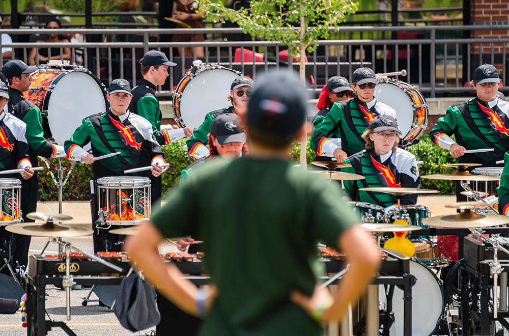 Blazer Band drum corps plays while a student looks on