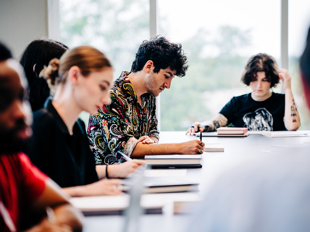 Students in a UAB classroom sitting around a large conference table take notes