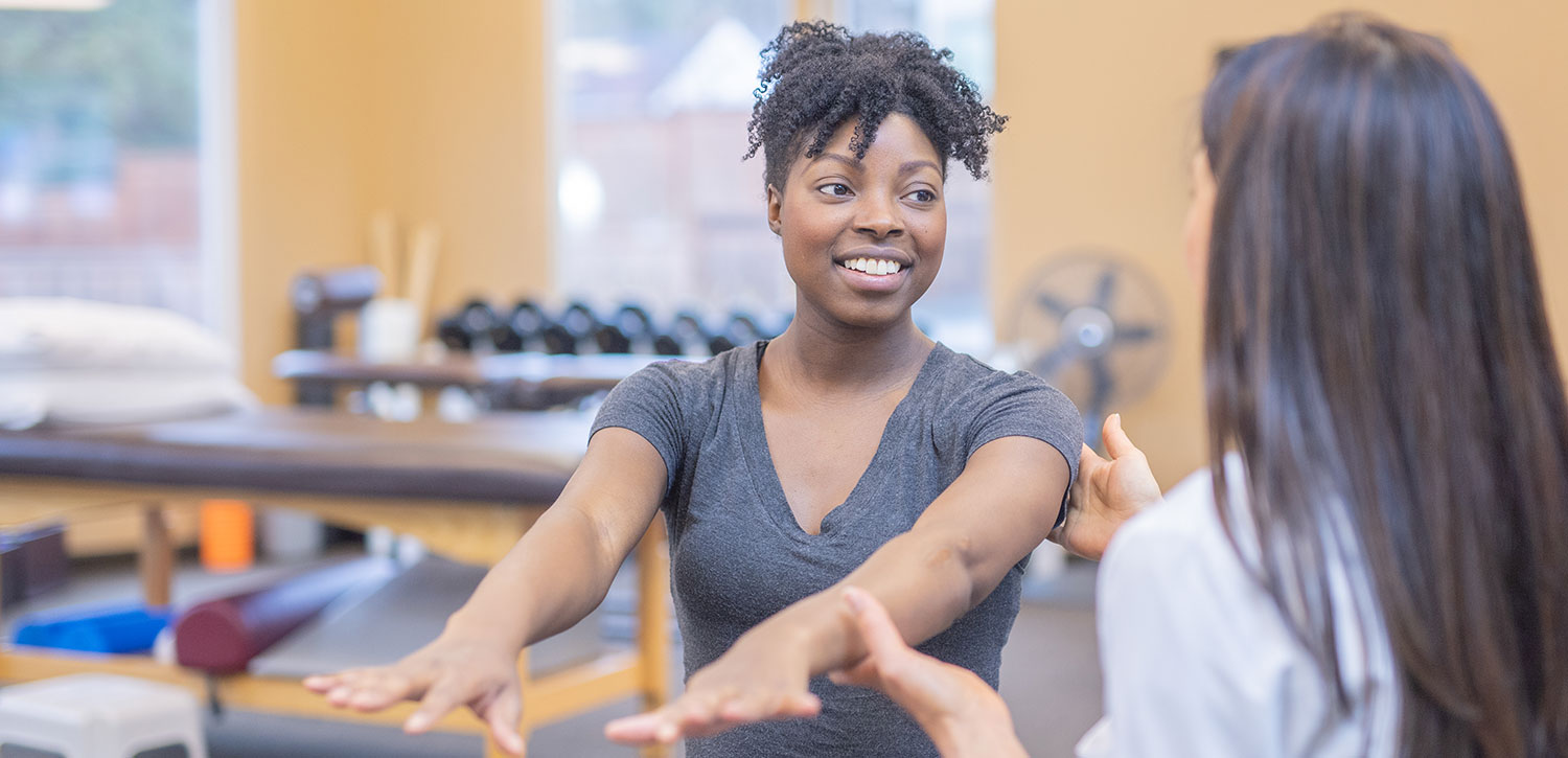 Physical Therapist helping woman stretch her arms.